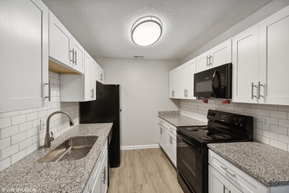 a kitchen with granite counter tops and white cabinets