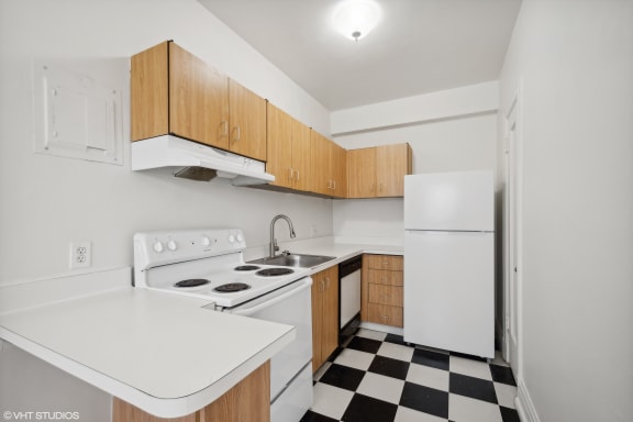 a kitchen with white appliances and wooden cabinets and a checkered floor at CWE Apartments, St. Louis, Missouri