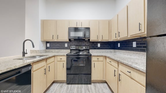 an empty kitchen with wood cabinets and black appliances at Bristol On Union Apartment Homes, Memphis, TN