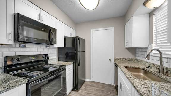 A kitchen with black appliances and white cabinets.