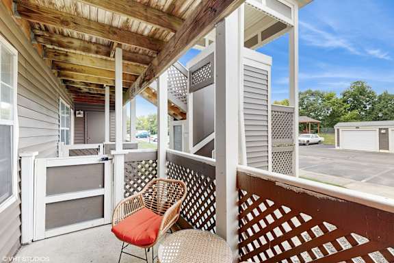a covered porch with two chairs and a table