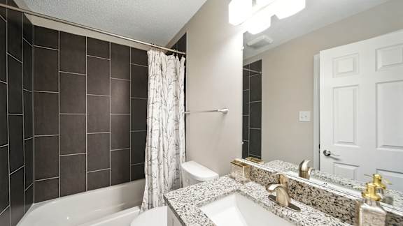 A bathroom with a white tub, sink, and shower curtain.