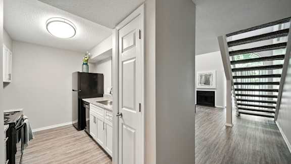 A kitchen with white cabinets and a black fridge is shown.
