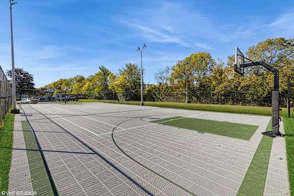 A basketball court with a green and grey surface and a basketball hoop on the right side at Island Club Apartments, Columbus, OH, 43235