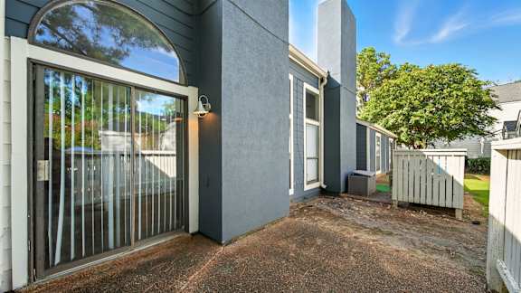 A grey house with a glass door and a small garden.