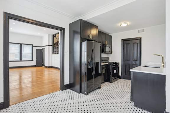 A kitchen with black cabinets and a black fridge.
