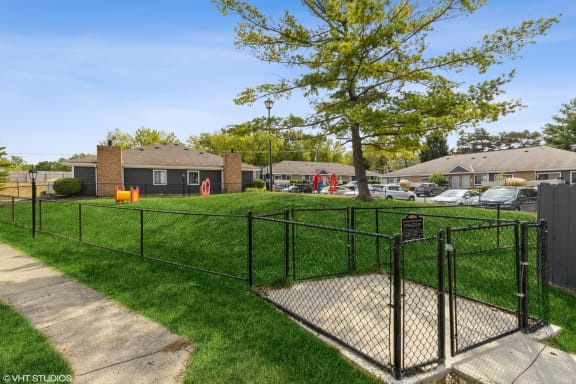 a fenced in dog park in a yard with a tree at Springburne at Polaris Apartments, Columbus, 43235