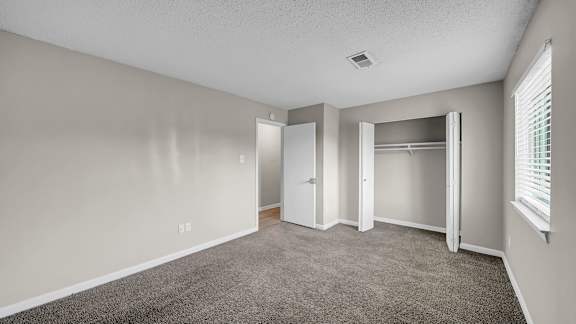A room with a carpeted floor and a window with blinds. at The Stella Apartments, Memphis, TN, 38134