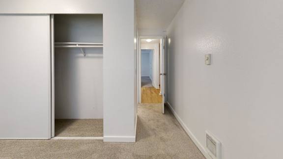 A white closet with a white door is open to a hallway.