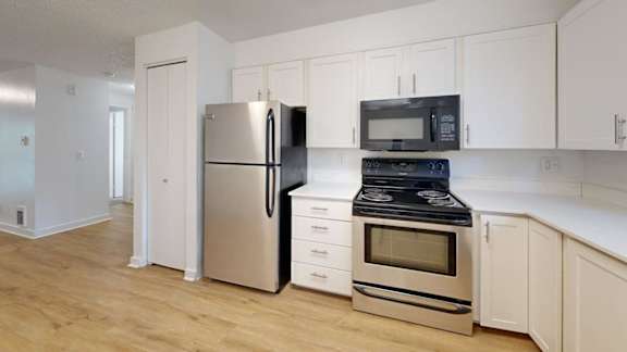 A kitchen with a refrigerator, oven, and microwave.