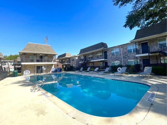 our apartments have a resort style pool with chairs at Tara Oaks in Houston, TX
