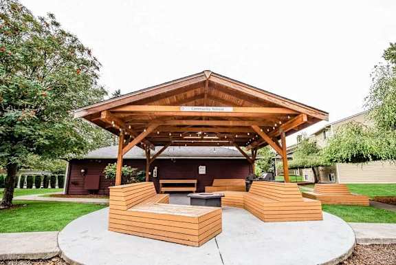 A wooden pavilion with a roof and a sign that reads "Community Center" is surrounded by a circular concrete patio.