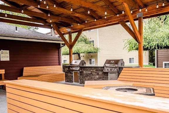 A wooden covered patio with a grill and picnic table.