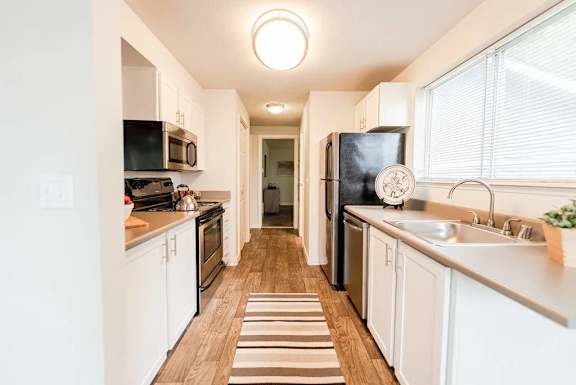 A kitchen with white cabinets and a striped rug on the floor.