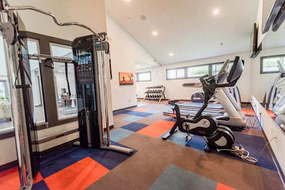 A gym with a treadmill, exercise bike and other equipment.