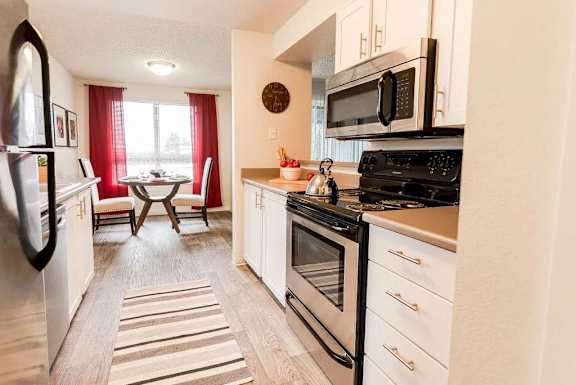 A kitchen with a black stove top oven and a black microwave above it.