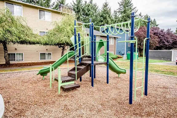 A playground with a green slide and a climbing frame.