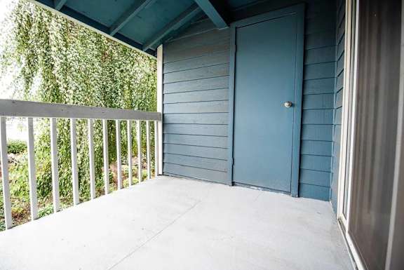 A blue door is on the right side of a porch.