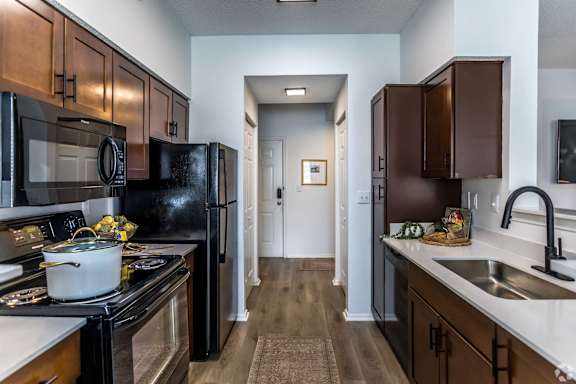 A kitchen with black appliances and wooden cabinets.
