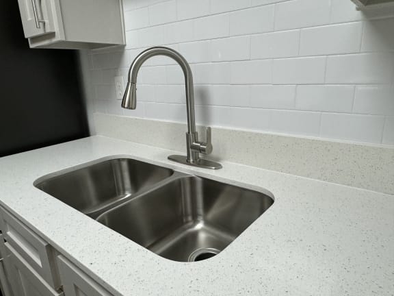 a kitchen sink with a chrome faucet in a white counter top