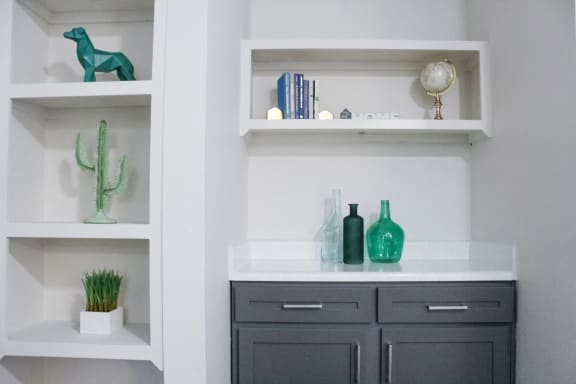 a bathroom with white walls and white cabinets with gray drawers and shelves