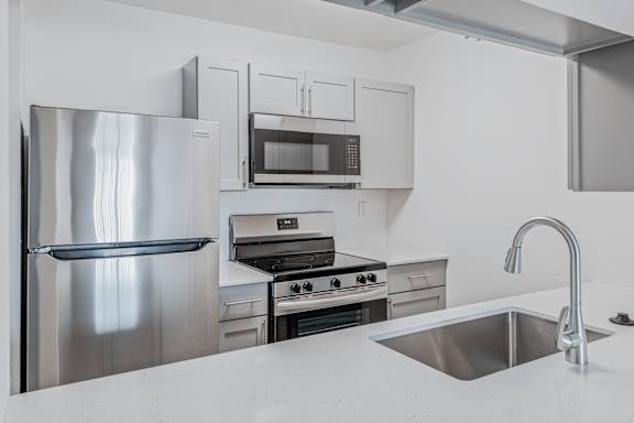 A modern kitchen with a stainless steel refrigerator, oven, and microwave at Water Ridge Apartments , Irving, Texas