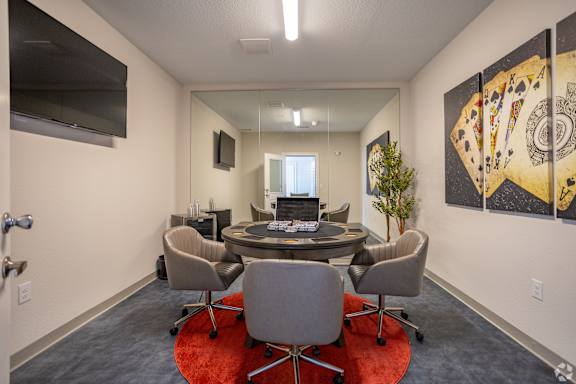 A conference room with a table surrounded by chairs and a television on the wall at The Virginia Apartments , Texas
