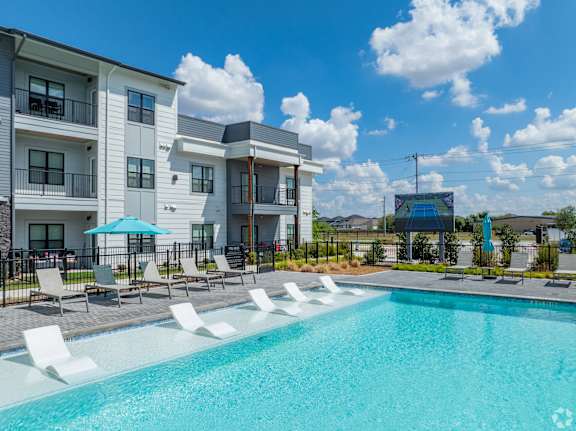 A swimming pool in front of apartment buildings at The Virginia Apartments , Seguin, Texas