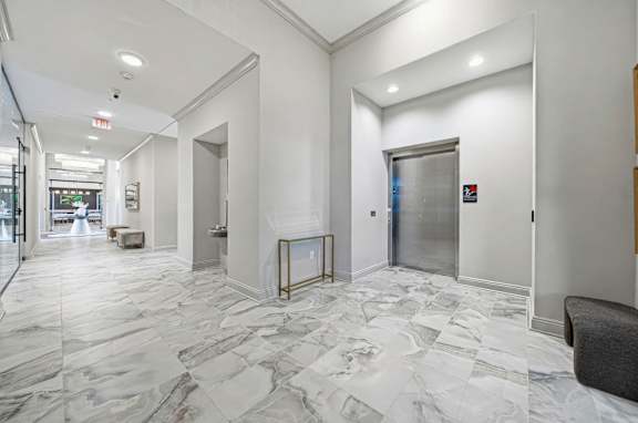 A hallway with marble floors and a bench.