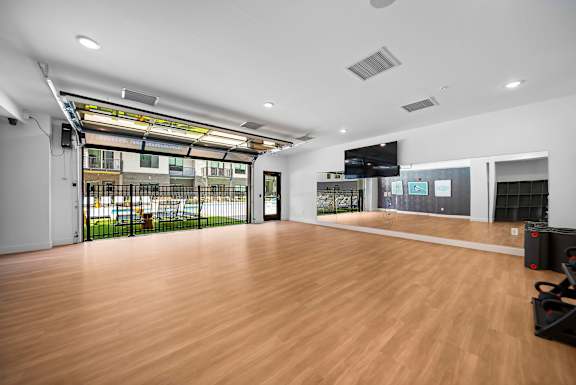 A room with a wooden floor and a large window with a view of a parking lot.