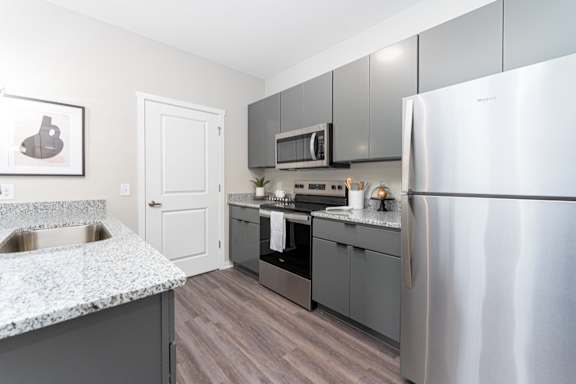 A kitchen with a stainless steel refrigerator, microwave, and oven.