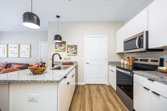 A kitchen with white cabinets and a granite countertop.