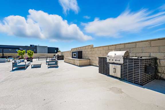 A rooftop patio with a grill and seating area.
