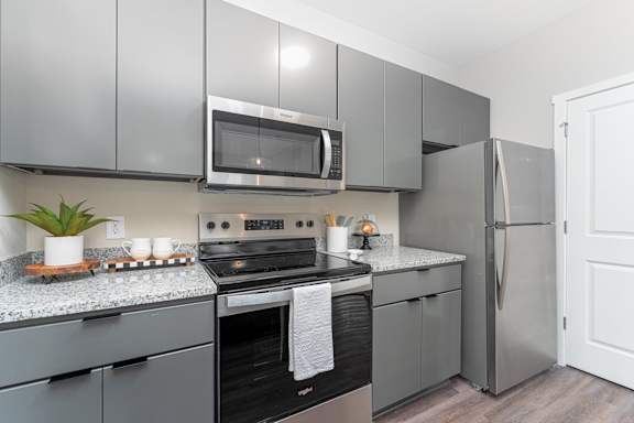 A modern kitchen with a black oven and a black and white towel hanging on the oven door.