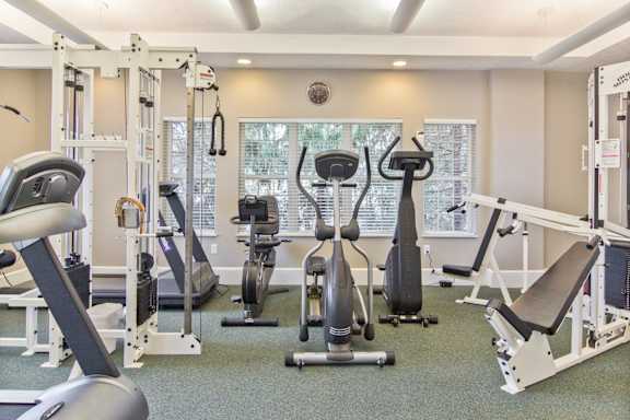 a gym with cardio equipment and weights on the floor