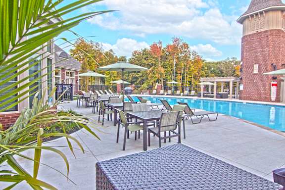 a swimming pool with tables and chairs next to a pool