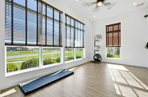 A room with a large window and a yoga mat on the floor.