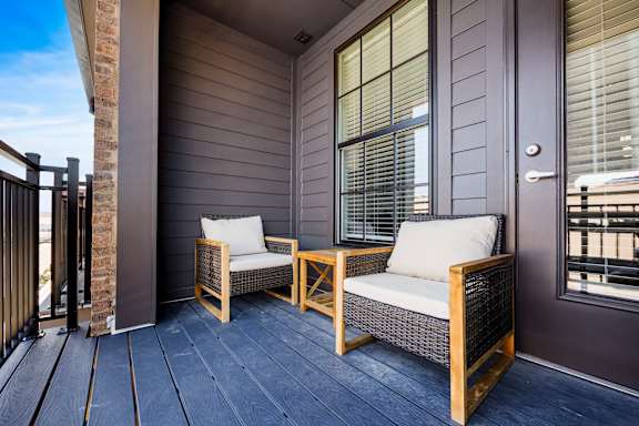 Two chairs and a table on a porch.