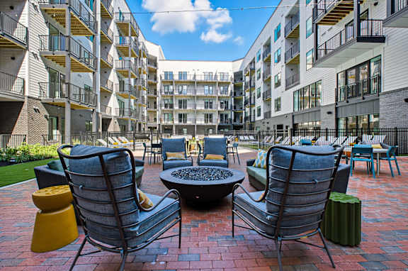 A patio with chairs and a table in front of apartment buildings.