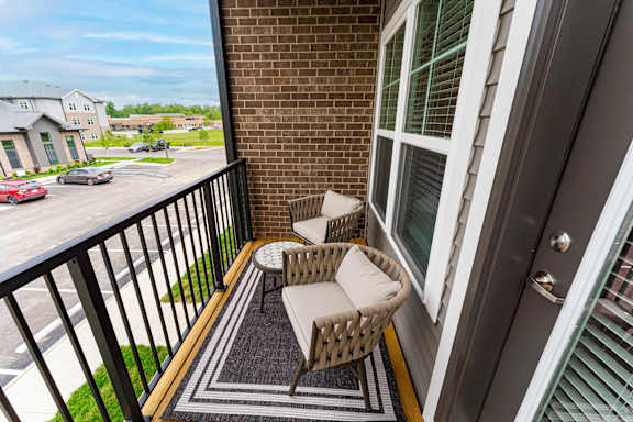 A balcony with a wicker chair and table.