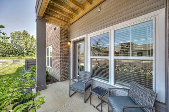 A patio with a couch, chair and table.