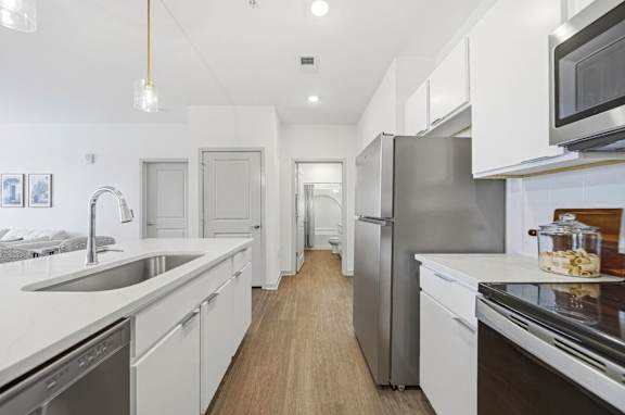A modern kitchen with white cabinets and stainless steel appliances.