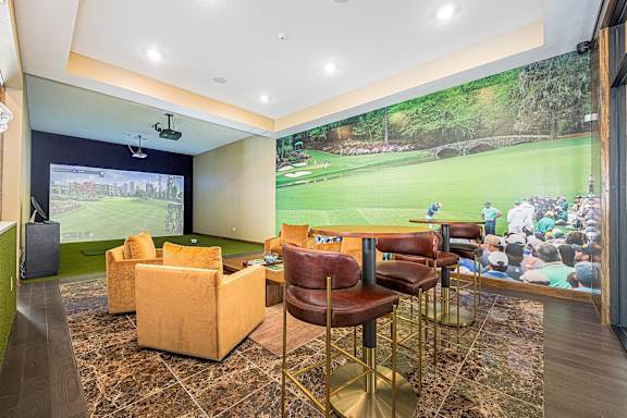 A room with a large screen and a bar area.
