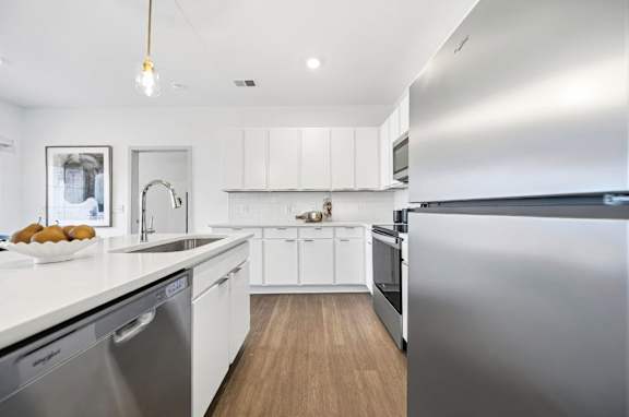 A modern kitchen with stainless steel appliances and white cabinets.