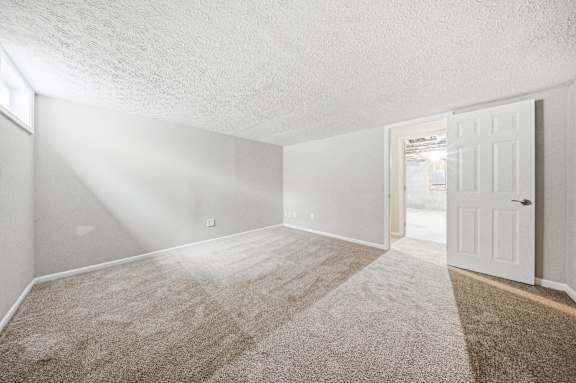 A room with a carpeted floor and a door on the right side.