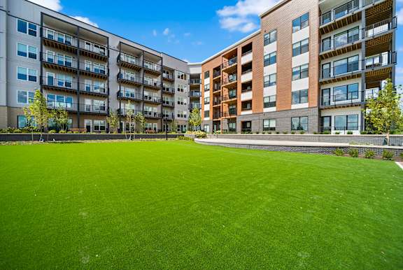 A large grassy area in front of apartment buildings.