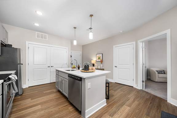 A kitchen with a refrigerator, sink, and cabinets.