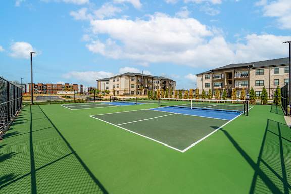 A tennis court surrounded by a fence and buildings.