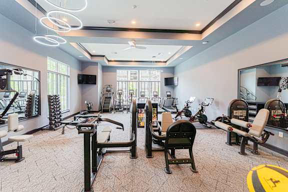 A spacious gym with various exercise equipment and mirrors.