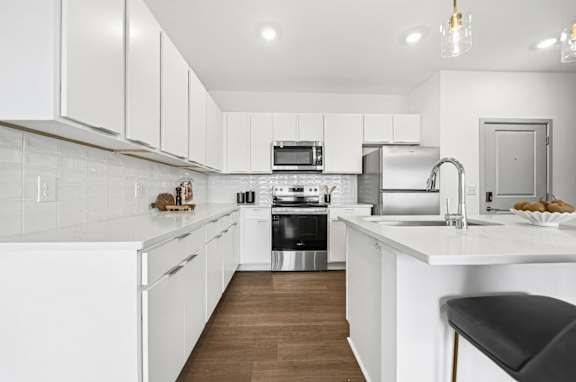 A modern kitchen with white cabinets and appliances.